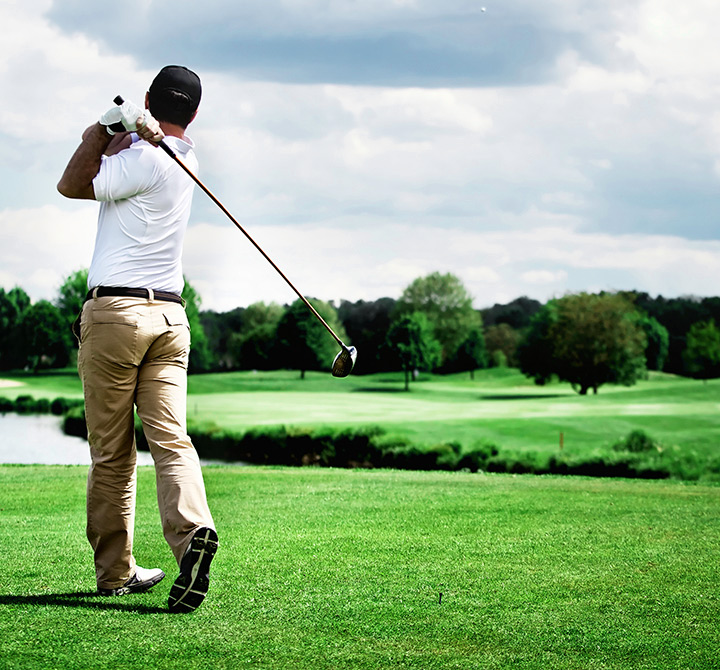 Male golfer mid-swing on a golf course.