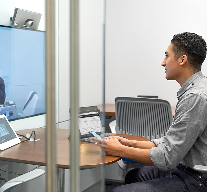 Man in office cubicle talking into video webcam.