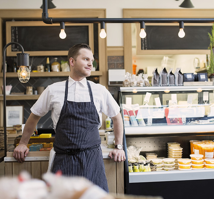 Small business owner in apron at a deli. 