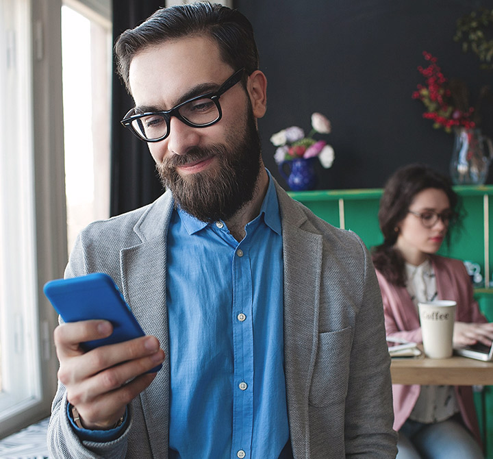 Man in blazer holding and looking at a smartphone. 