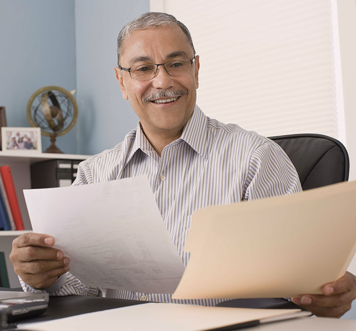 Man reviewing paperwork while sitting at his desk.