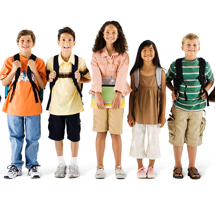 Group of five school kids smiling with their school bags.