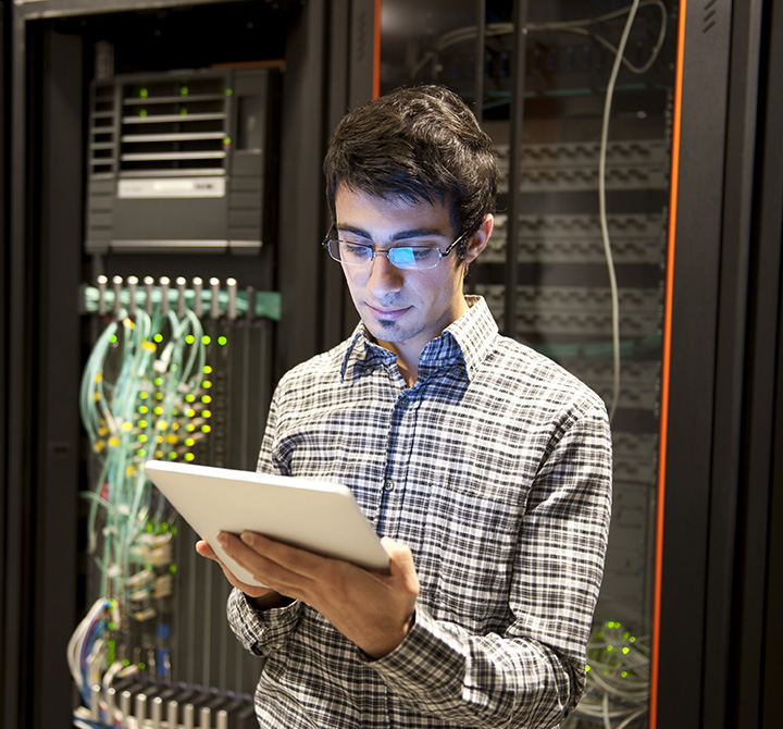 IT person in front of servers holding a tablet.