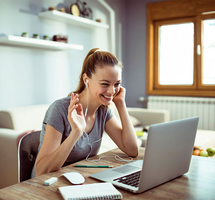Woman waving at laptop in living room