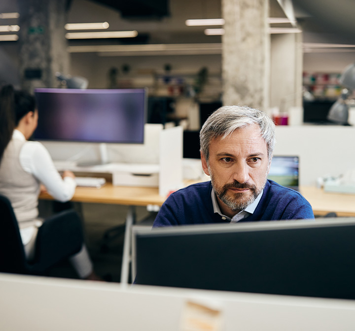 Man working in front of computer monitor in office.