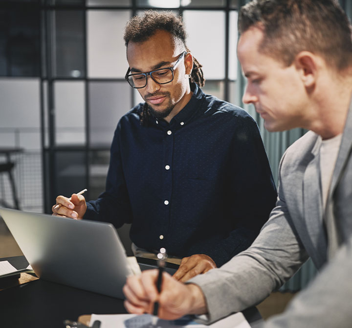Two men looking at laptop in office.