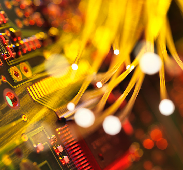 Computer chip with yellow fiber optic wires in front of it.