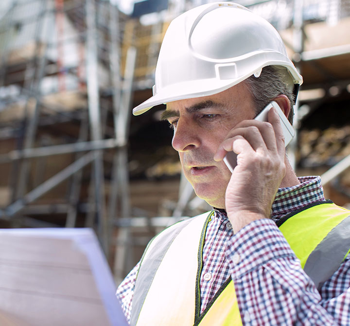 Man wearing hardhat at construction site talking on a cellphone