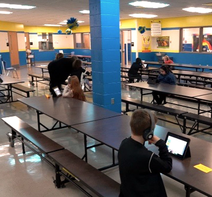 Children in a lunch room using tablets.