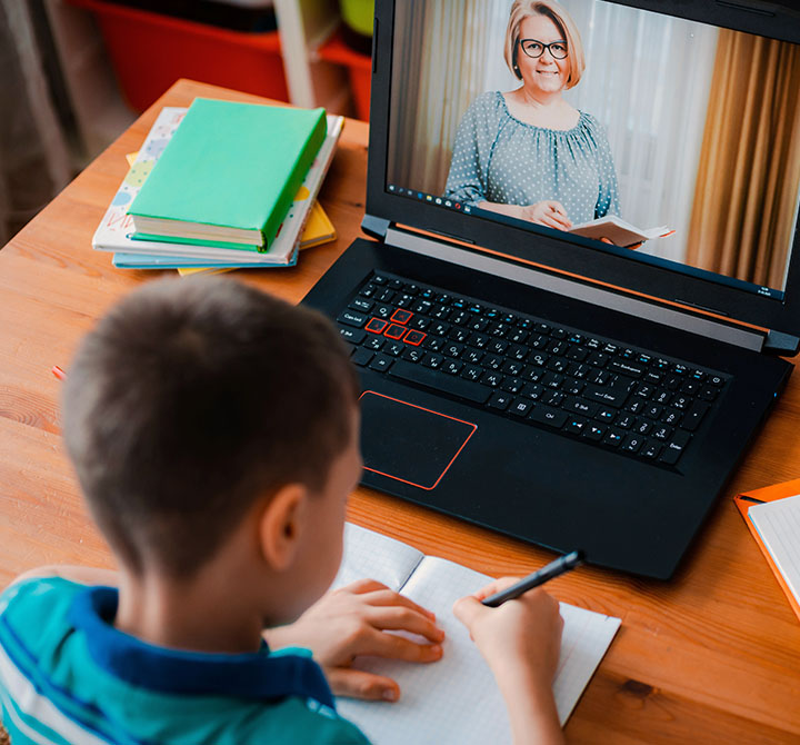 Young boy doing home work in front of a laptop.