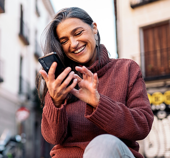 Businesswoman in a red sweater reviewing offer terms on a cell phone in a public. square.
