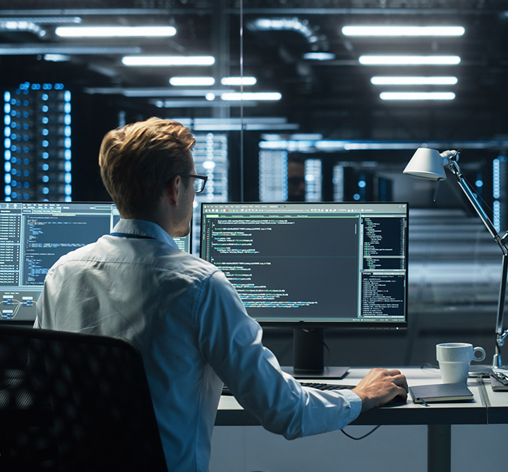 Man in data center working with code on a monitor