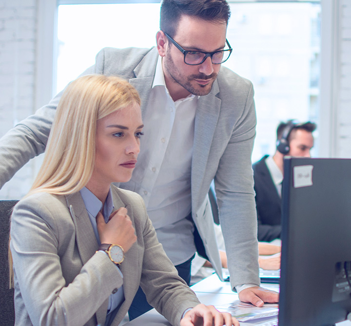 Business associates in an office looking at a monitor