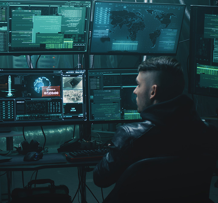 Man in a security data center viewing dashboards and code on multiple monitors