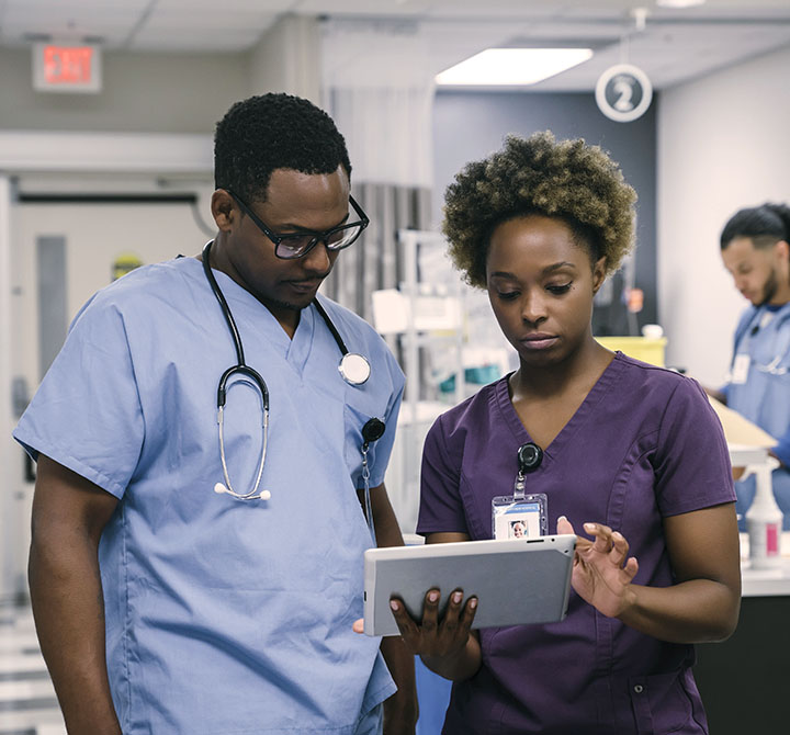 Two healthcare professionals talking over a tablet