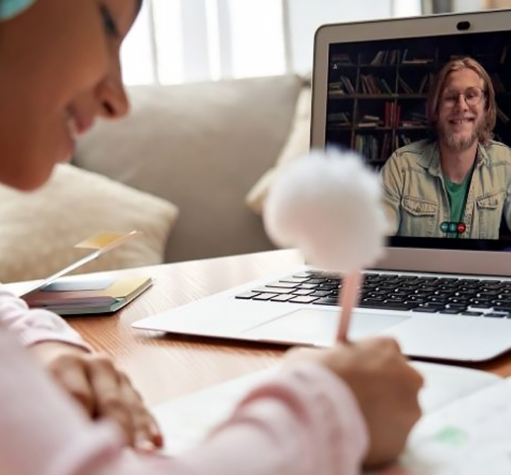 A student is sitting at a desk in a virtual teaching session on his laptop computer connected using fast, reliable AT&T Fiber.