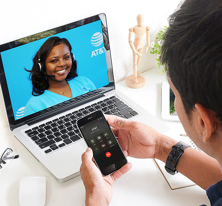 A female AT&T employee wearing a headset is on a video and conference call with a customer.