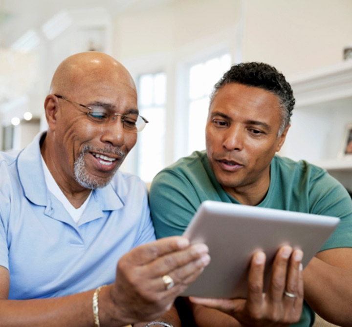 Two men seated looking at tablet with health information.