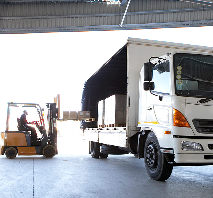 Forklift loading boxes into a white freight truck.
