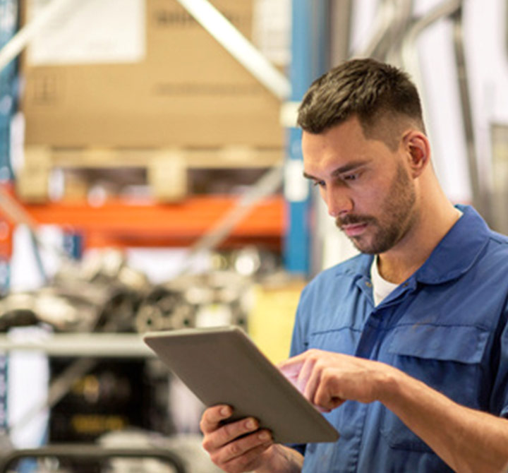 Man in warehouse holding a tablet. 