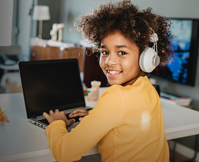 Grade school boy on laptop with headphones