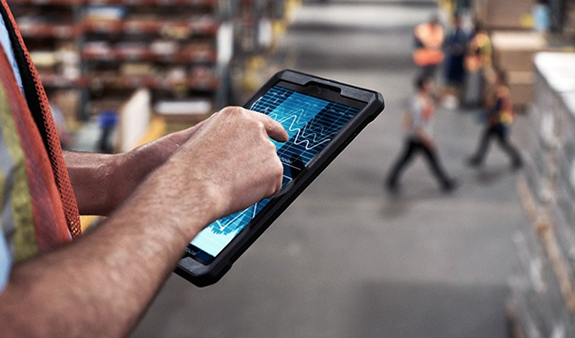 Close up view of the hands of a male worker, in a warehouse, doing his work from a tablet device he is holding.