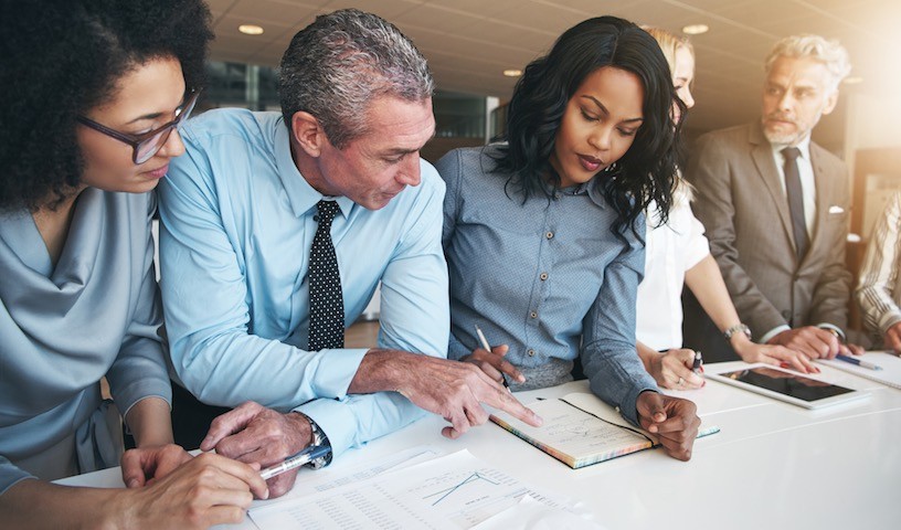 Black and white group of people doing teamwork in contemporary office.
