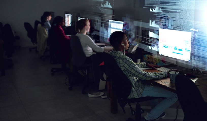 Rear view shot of a team of programmers coding through the night