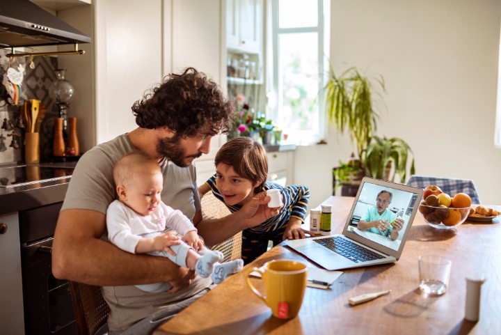 Close up of a single father with his kids consulting with their doctor over a video call on the laptop