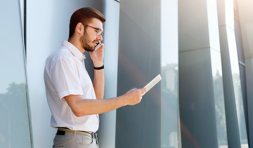 Man standing in front of an building using his cell phone