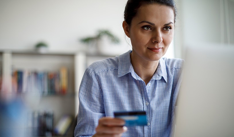Woman sitting at a desk on a laptop with credit card in hand