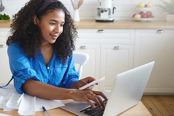 Woman sitting at table with laptop and receipts