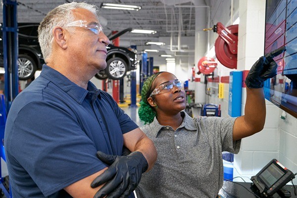 Man and woman in mechanic garage looking at diagnostic screen