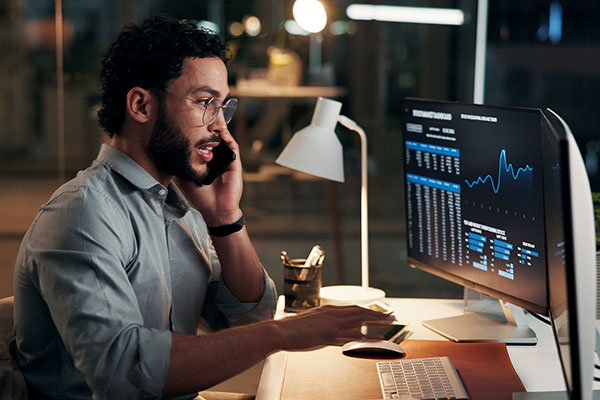 Phone call, computer and businessman in office at night for finance negotiation with client. Cellphone, stock market and financial advisor on mobile discussion for investment proposal in workplace