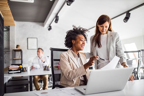 Two brunette business woman, talking, advising each other.