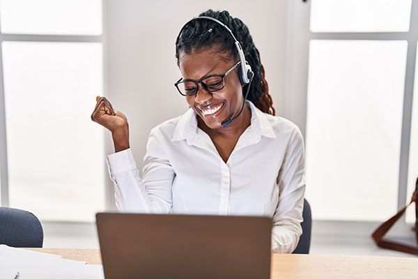 African woman with braided hair wearing call center agent headset screaming proud, celebrating victory and success very excited with raised arm 