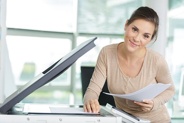 a smiling woman makes photocopies