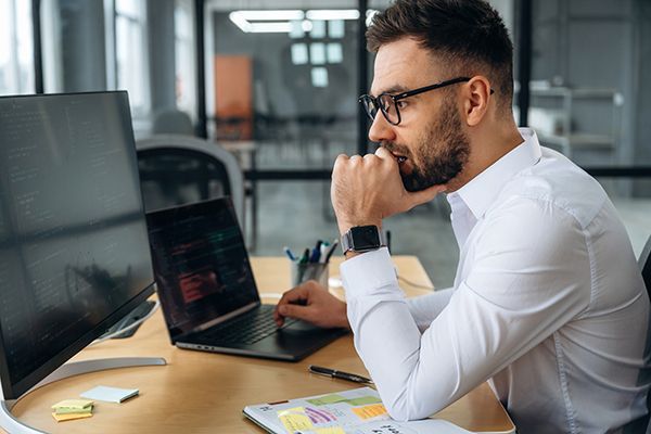 View from the side. Business person is sitting by computer in office and working.