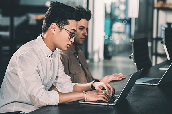side view of multicultural businessmen working at table with laptops at modern office 