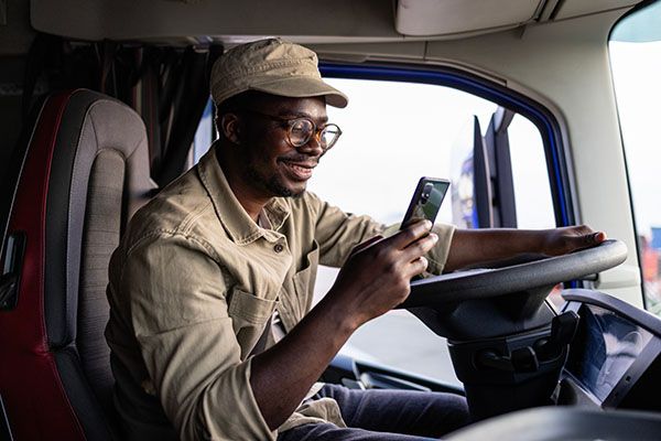 Professional driver sitting in his truck and using smart phone.