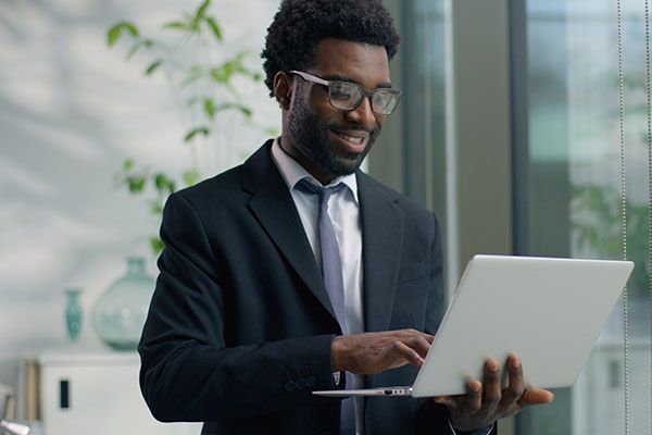 Concentrated pensive African American business man typing laptop in office looking at window smiling thoughtful focused ethnic businessman male professional working computer internet corporate agent. High quality 4k footage