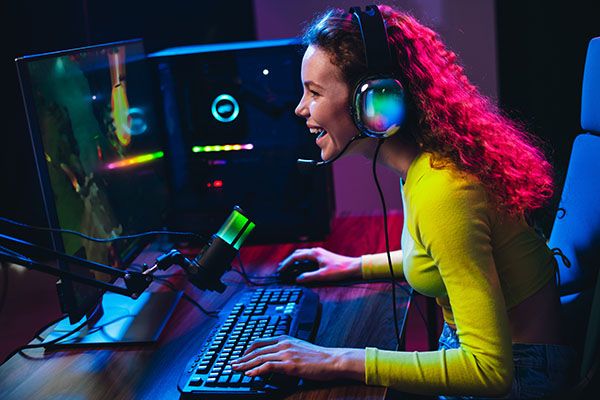 Young woman enjoying online video gaming at home, using professional gaming equipment under neon lights, engaged in streaming.