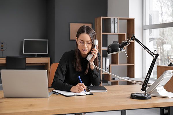 Young secretary talking on telephone in office