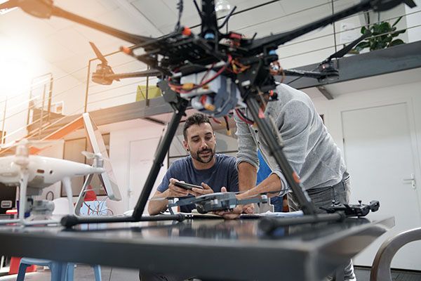 Engineer and technician working together on drone in office
