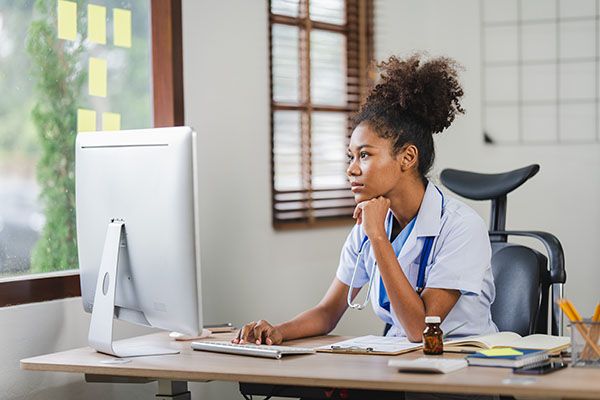 African american female doctor sitting in front of computer at her clinic office