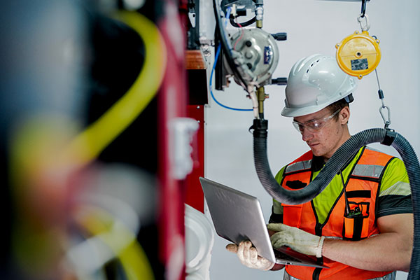 Man on laptop in manufacturing facility