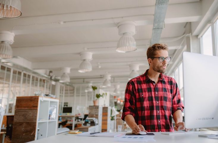Shot of young businessman in casual clothes at modern startup business office space, working on desktop computer.