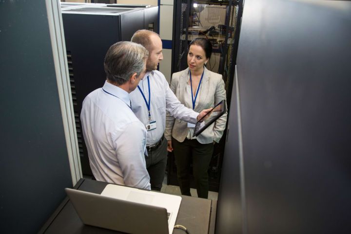 Computer technicians having discussion on digital tablet in server.