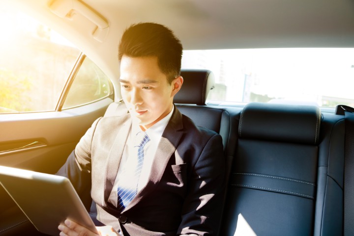 young businessman using tablet pc in car at morning