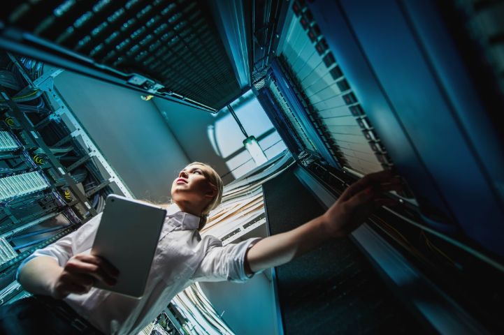Young engineer businesswoman in network server room. Russia.